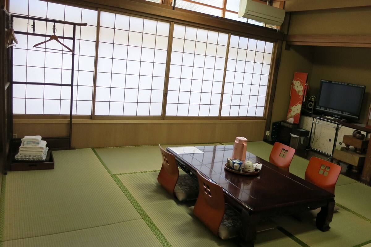 Una habitación japonesa tradicional con suelo de tatami, una mesa baja y un televisor.