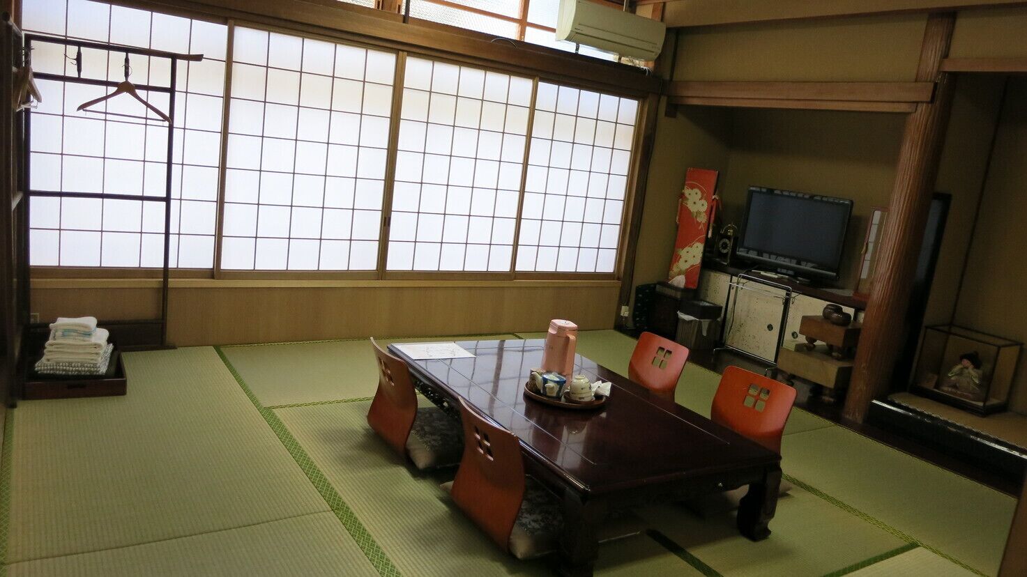 Una habitación japonesa tradicional con suelo de tatami, una mesa baja y un televisor.