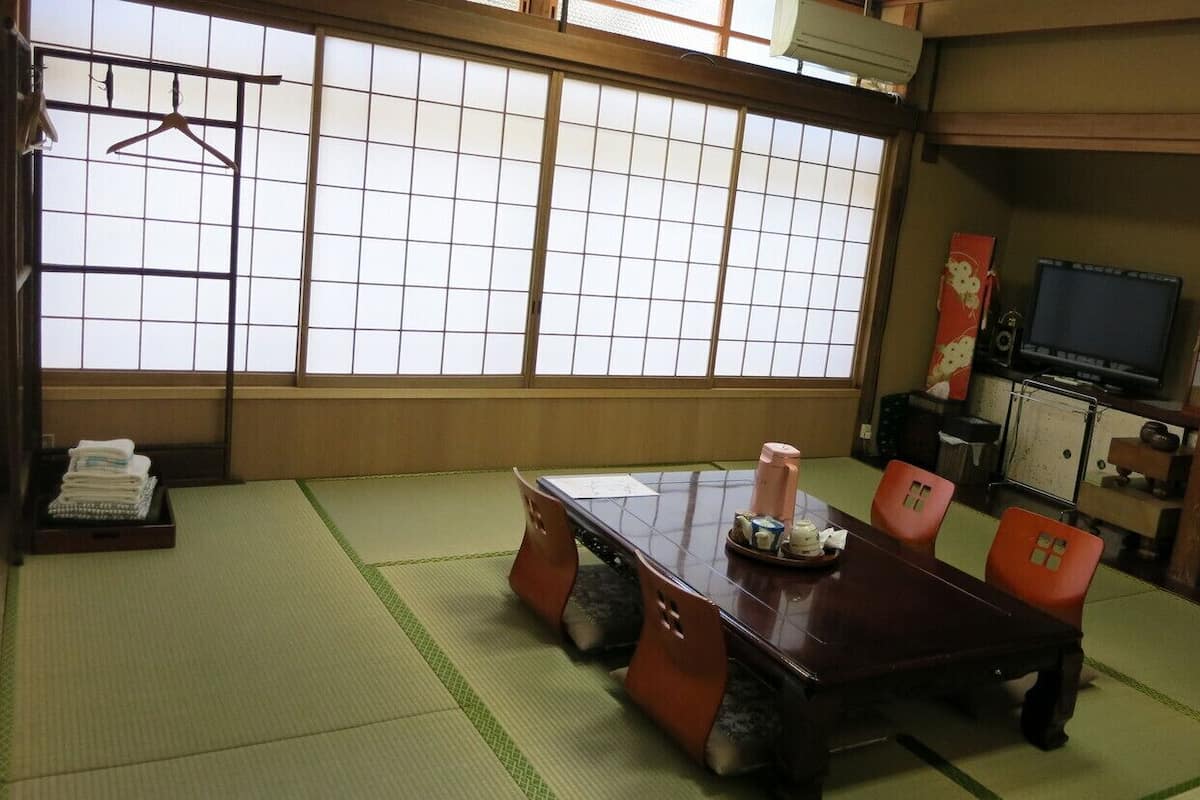 Una habitación japonesa tradicional con suelo de tatami, una mesa baja y un televisor.