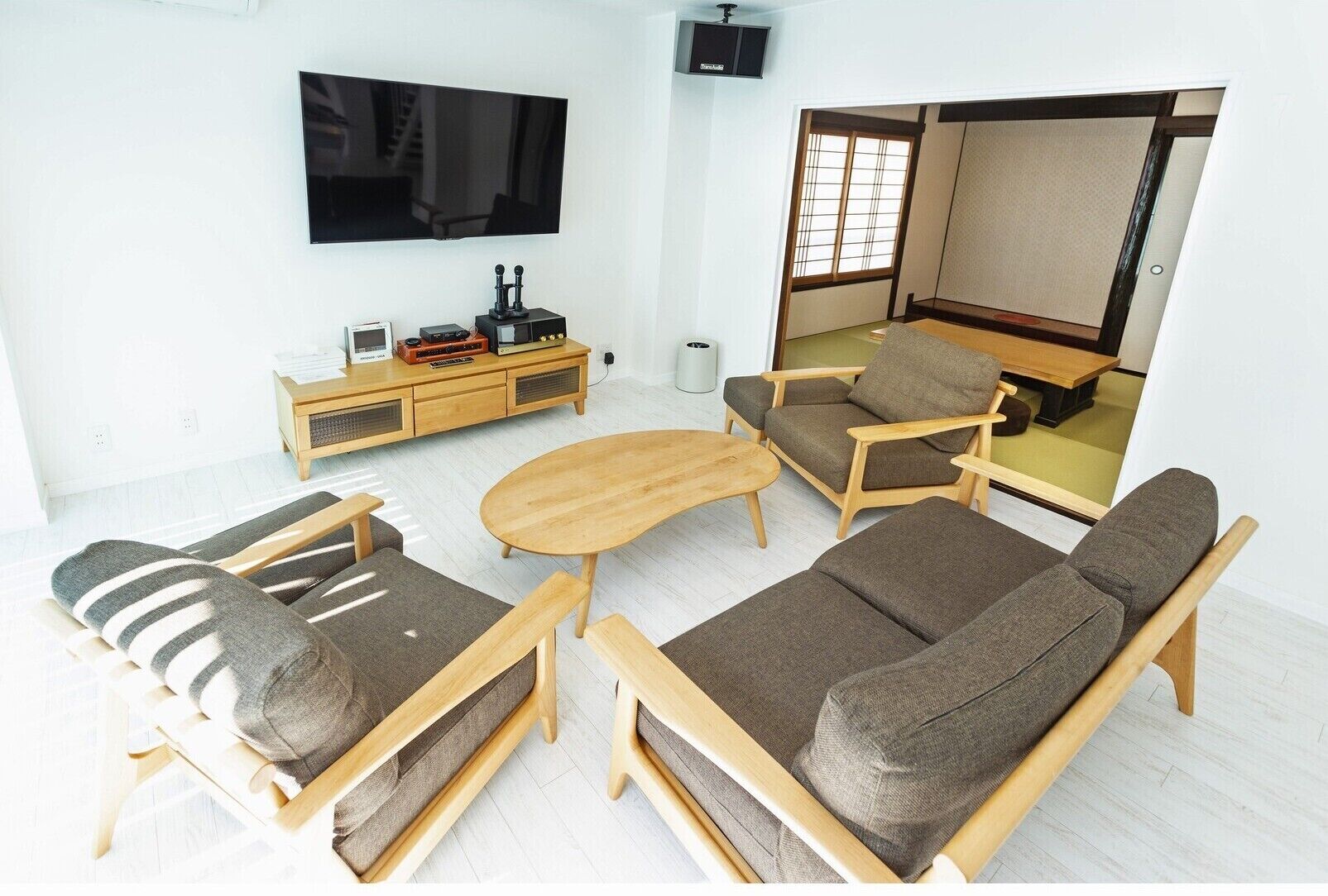 Una sala de estar moderna con un juego de sofá, una mesa de centro, un televisor y un mueble con dispositivos electrónicos.