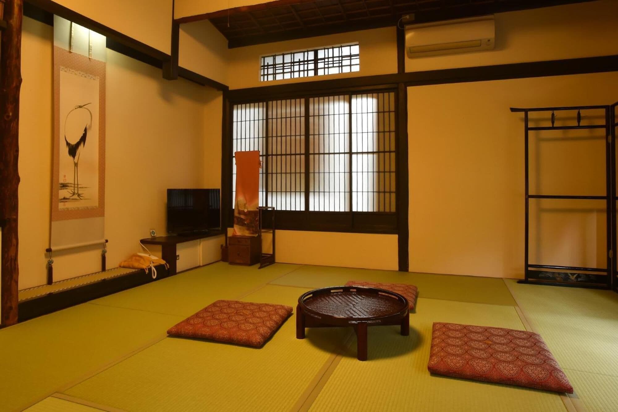 A traditional tatami mat room with a tatami mat floor, a round wooden table, and a sliding door with a grid pattern.
