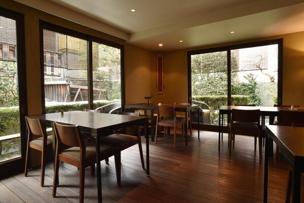 A spacious dining area with large windows, wooden flooring, and multiple tables and chairs. - Yadoya Nishijinso (Kyoto)