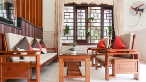 A traditional-style living room with wooden furniture, a glass coffee table, and a view of a wooden staircase. - Viet Nhat Homestay (Da Nang)