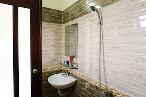 A bathroom with a wooden and marble tiled wall, a glass shelf with toiletries, and a shower. - Viet Nhat Homestay (Da Nang)