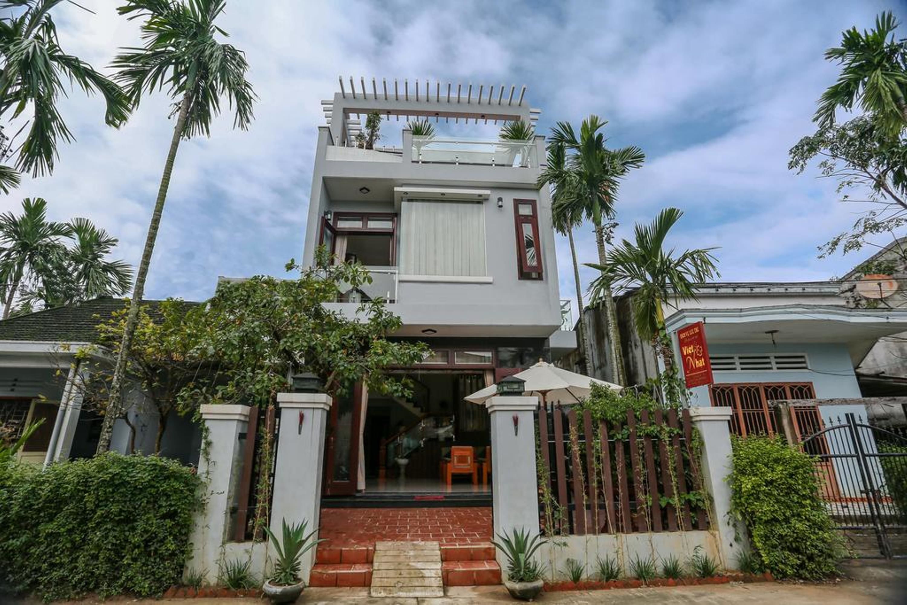 A two-story house with a balcony, a gated entrance, and a red sign.