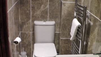 Un baño con inodoro, lavamanos y perchero para toallas.