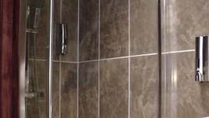 Eine moderne Duschkabine mit Glastür, Handbrause und am Wand montierter Armatur.