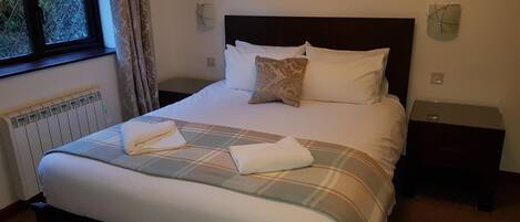 A neatly made bed with a plaid bedspread and pillows, a world map on the wall, and a window with curtains.