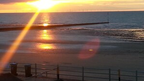 A sunset over a beach with a pier extending into the water. - Bay Lodge (Birchington)