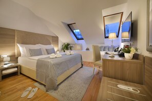 Quarto de hotel moderno com uma cama grande, uma escrivaninha, uma cadeira e um claraboia.