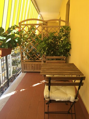 A balcony with a wooden table and bench, surrounded by potted plants and a lattice fence. - Il Saraceno (Sorrento)