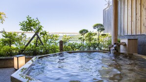 A hot spring area with a wooden structure, a view of the sea, and a sign in Japanese. - Toba Seaside Hotel (Toba)
