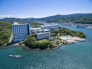 An aerial view of a coastal hotel complex with multiple buildings, a swimming pool, and a dock. - Toba Seaside Hotel (Toba)