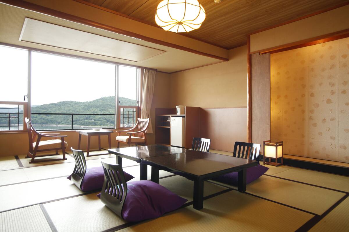 A traditional Japanese room with tatami flooring, a low table, and chairs.