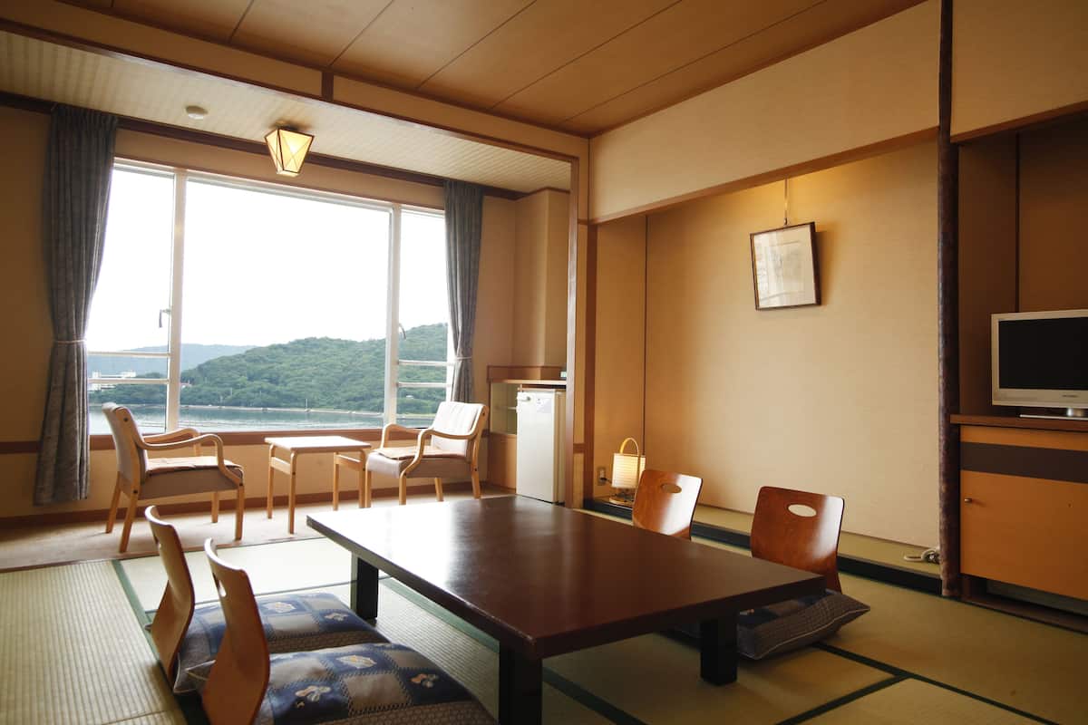 A traditional Japanese room with tatami flooring, a low table, and a television on a wooden cabinet.