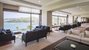 A spacious hotel lobby with a large seating area, a dining section, and a view of a lake. - Toba Seaside Hotel (Toba)