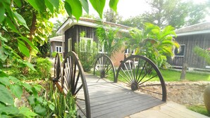 A wooden deck leading to a rustic building with a brick facade and large wheels on the front. - KMA Bagan Village Hotel (Nyaung-U)