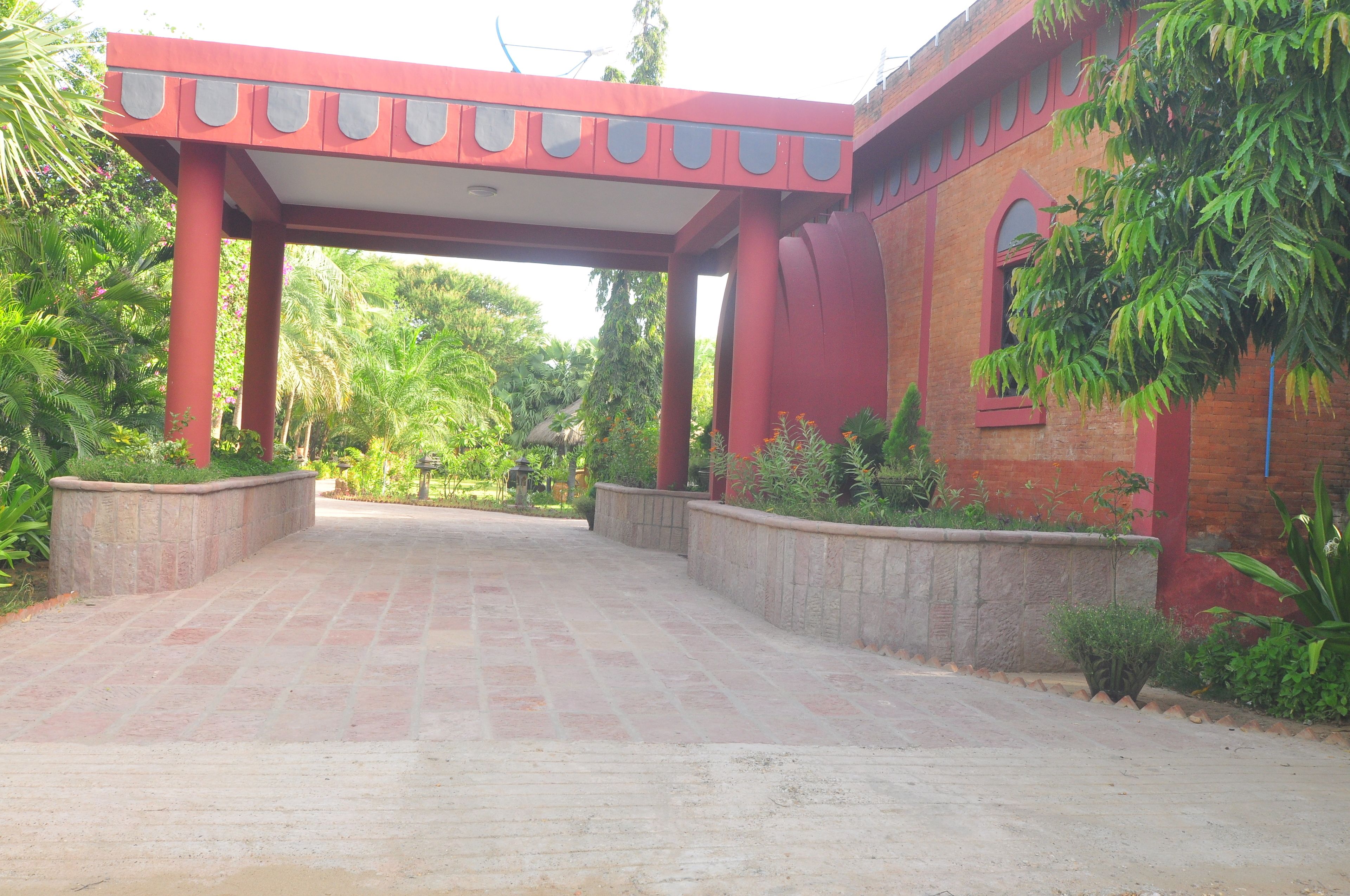 A red-brick building with a covered entrance and a paved pathway leading to it.