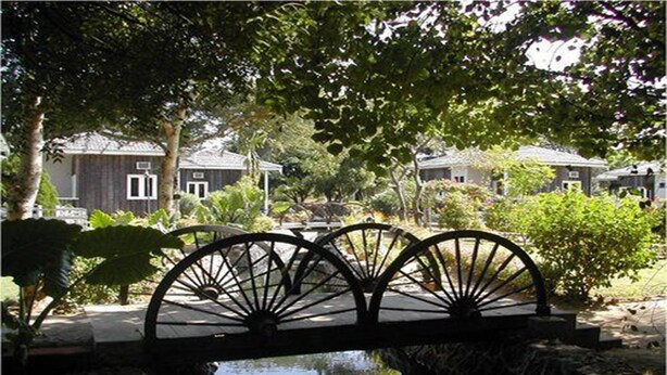 A bridge with a waterway underneath, surrounded by greenery and buildings with a traditional architectural style. - KMA Bagan Village Hotel (Nyaung-U)
