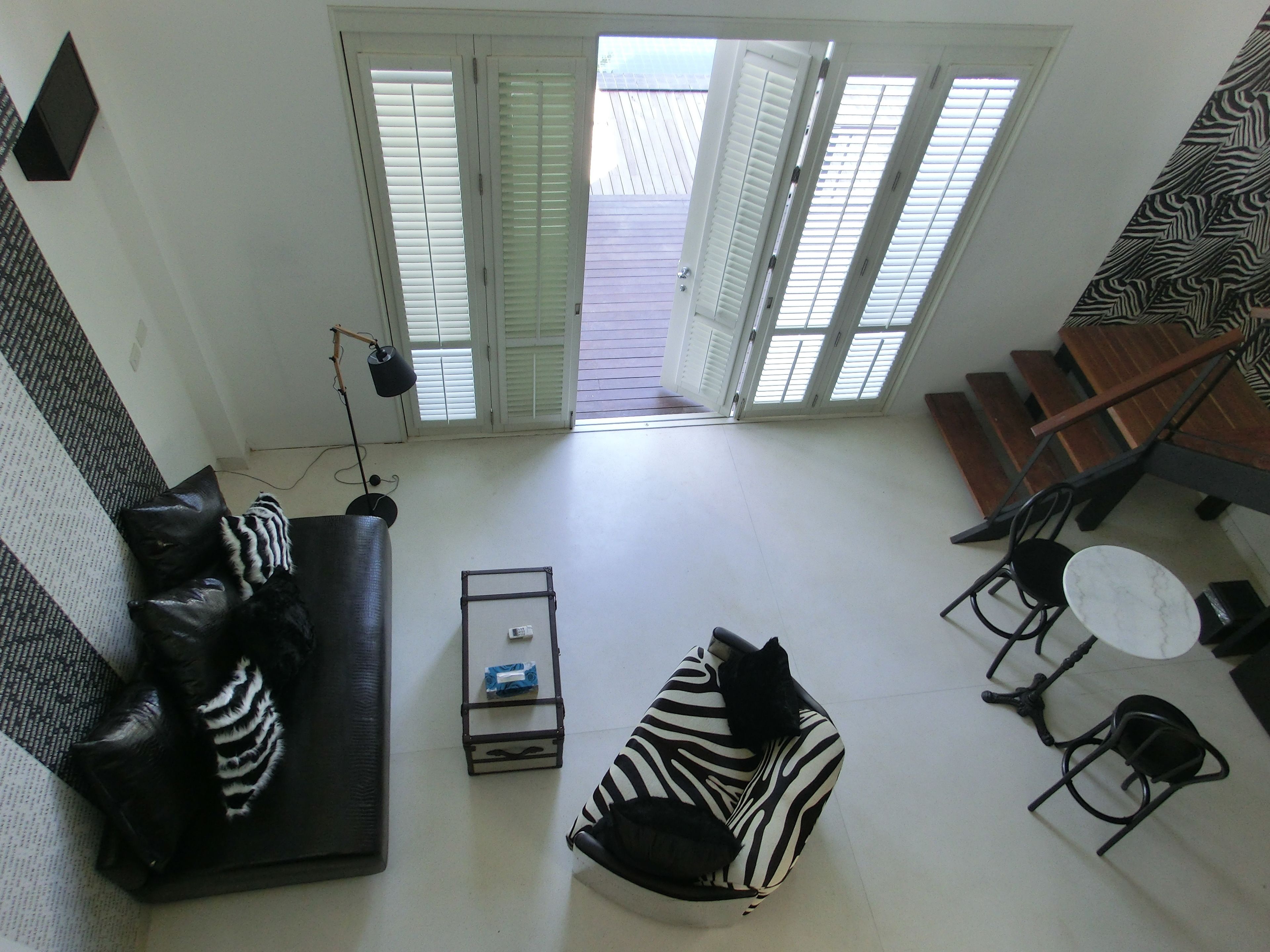 A living room with a black and white striped sofa, a small table with a lamp, and a staircase leading to an upper level.