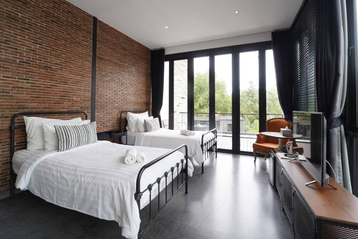 A modern hotel room with two beds, a desk, and a large window with a view.