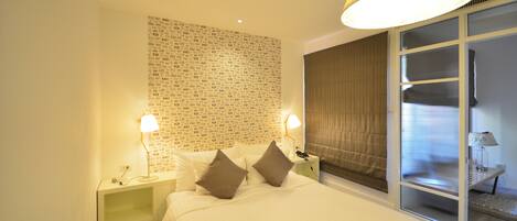 A hotel room with a large bed, two bedside lamps, a wall with text, and a window with curtains.
