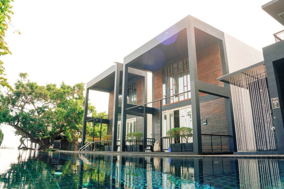 A modern hotel with a swimming pool, large windows, and a brick facade.