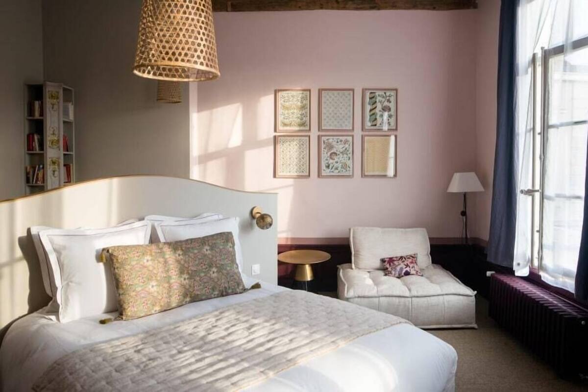 Un dormitorio con una cama, una silla, una mesita y una estantería.