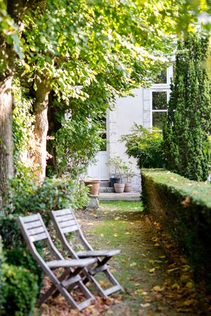 A garden with a bench, a potted plant, and a hedge. - Maison Ailleurs (Chartres)