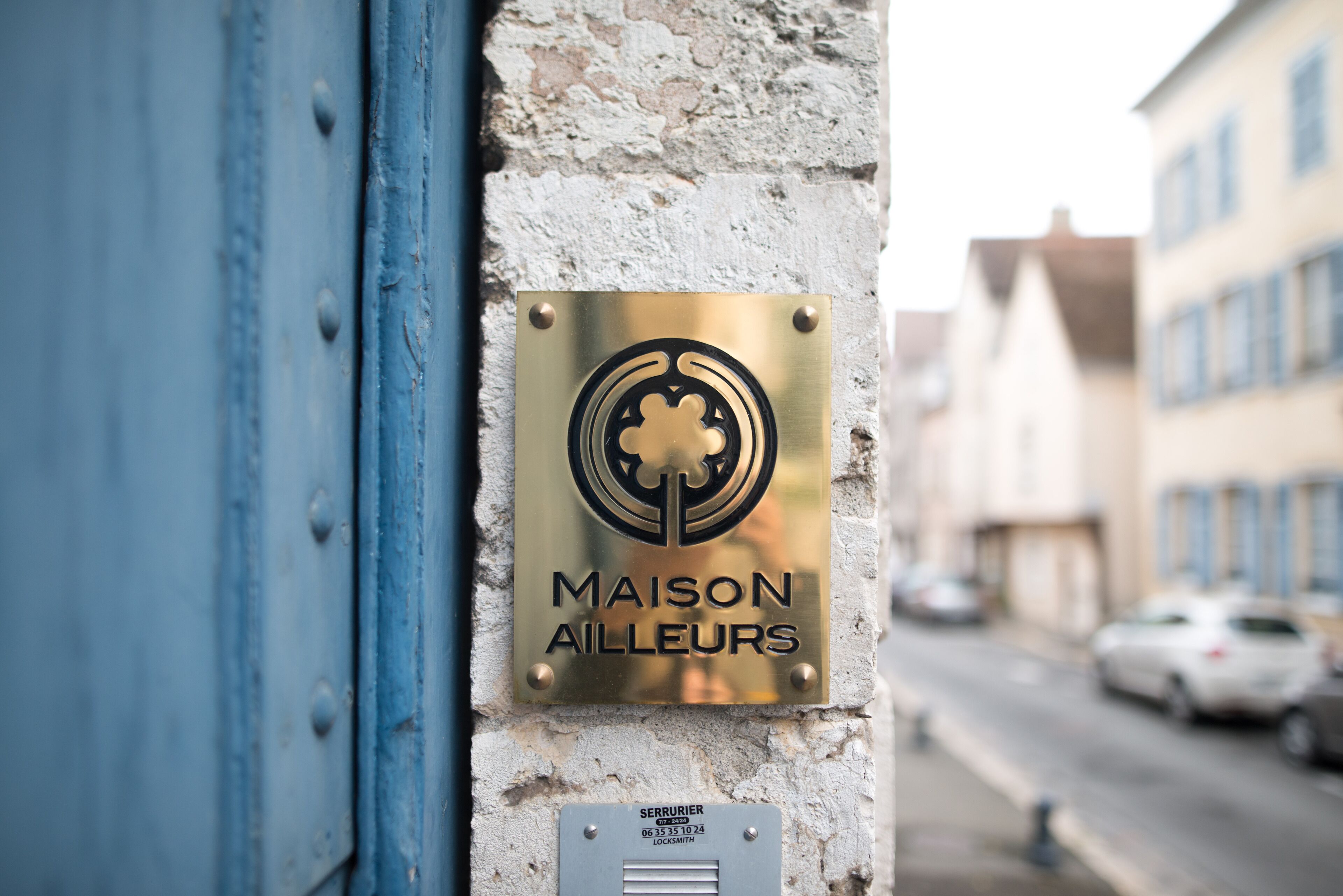 A brass plaque with the text "MAISON AILLEURS" on a building facade.