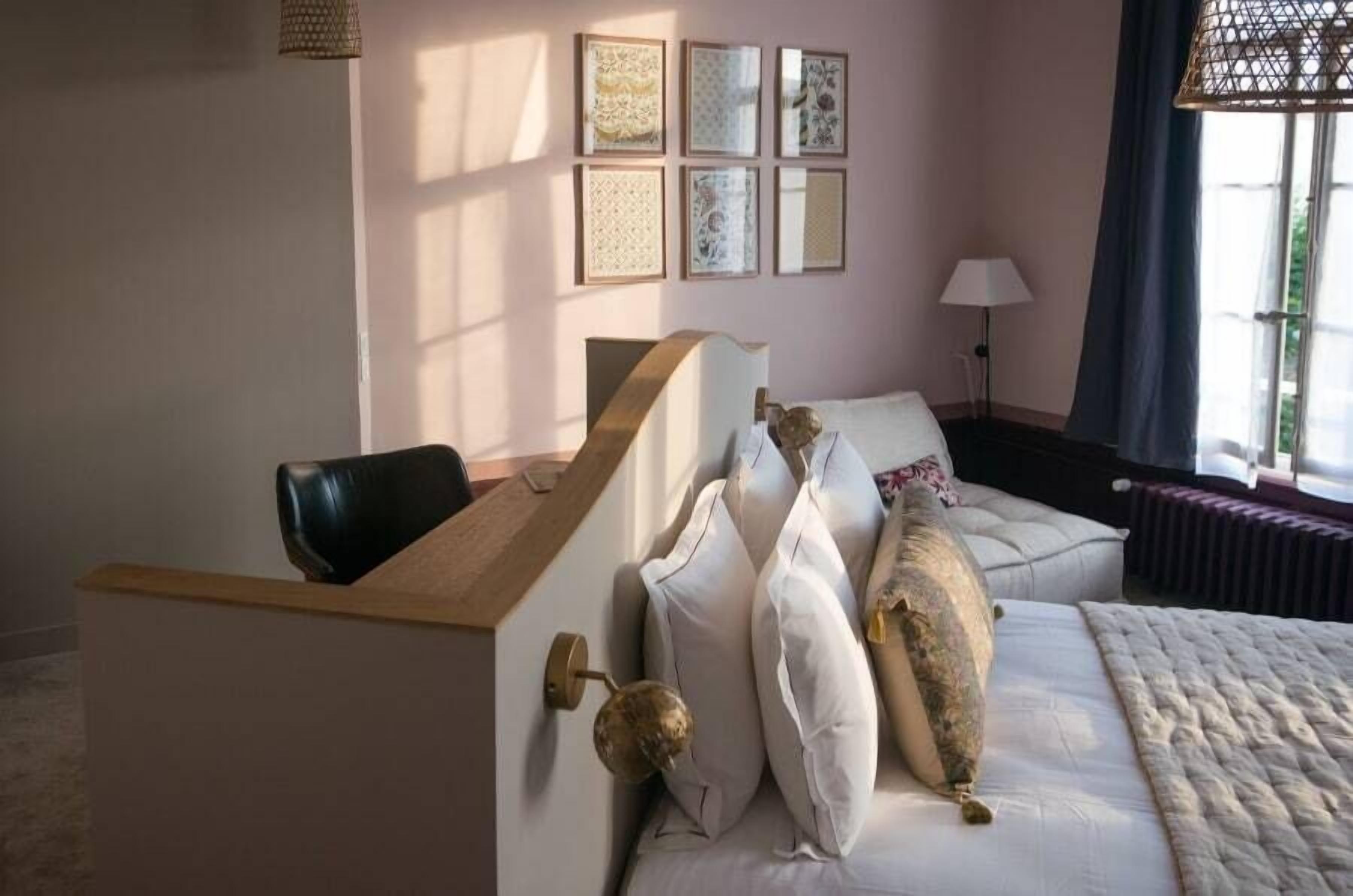 Een slaapkamer met een bed, een stoel, een bureau en een raam met gordijnen.