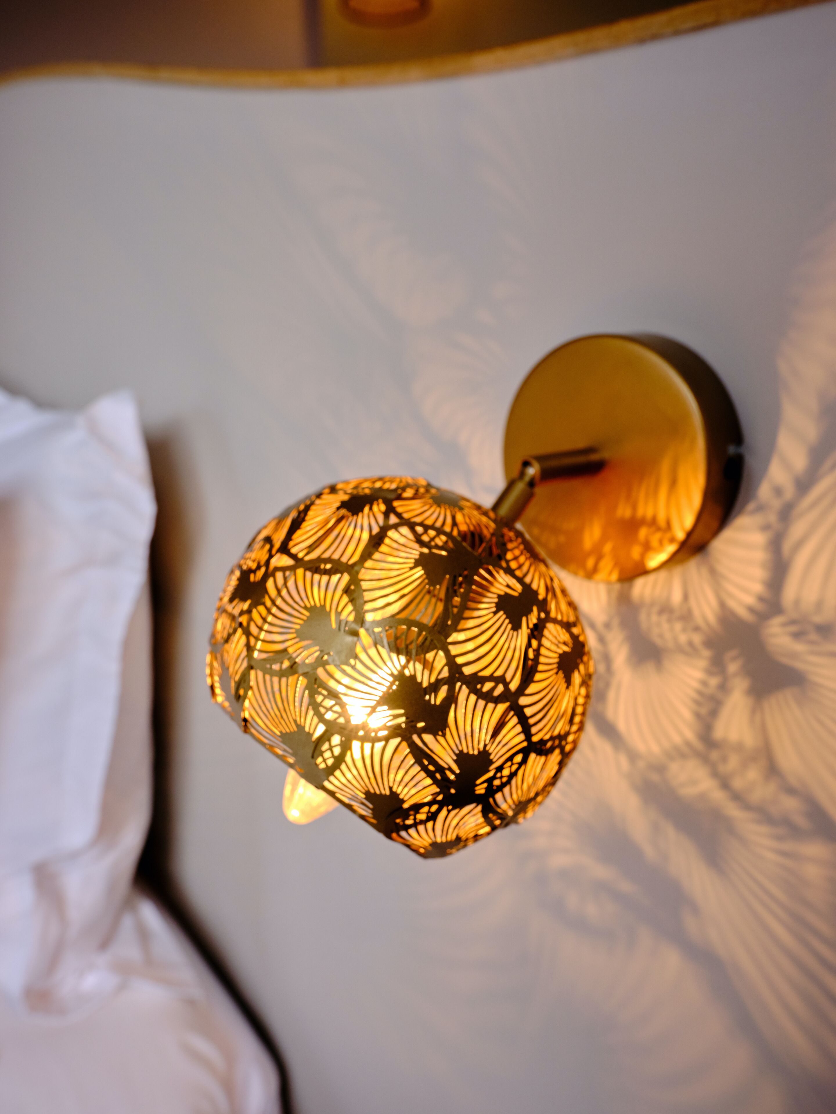 Een wandlamp met een lampenkap met een patroon.