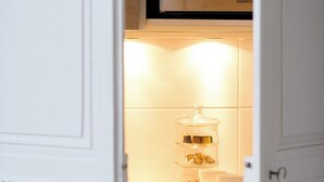 Cozinha com micro-ondas, um recipiente de vidro com alimentos e uma xícara de café sobre o balcão.
