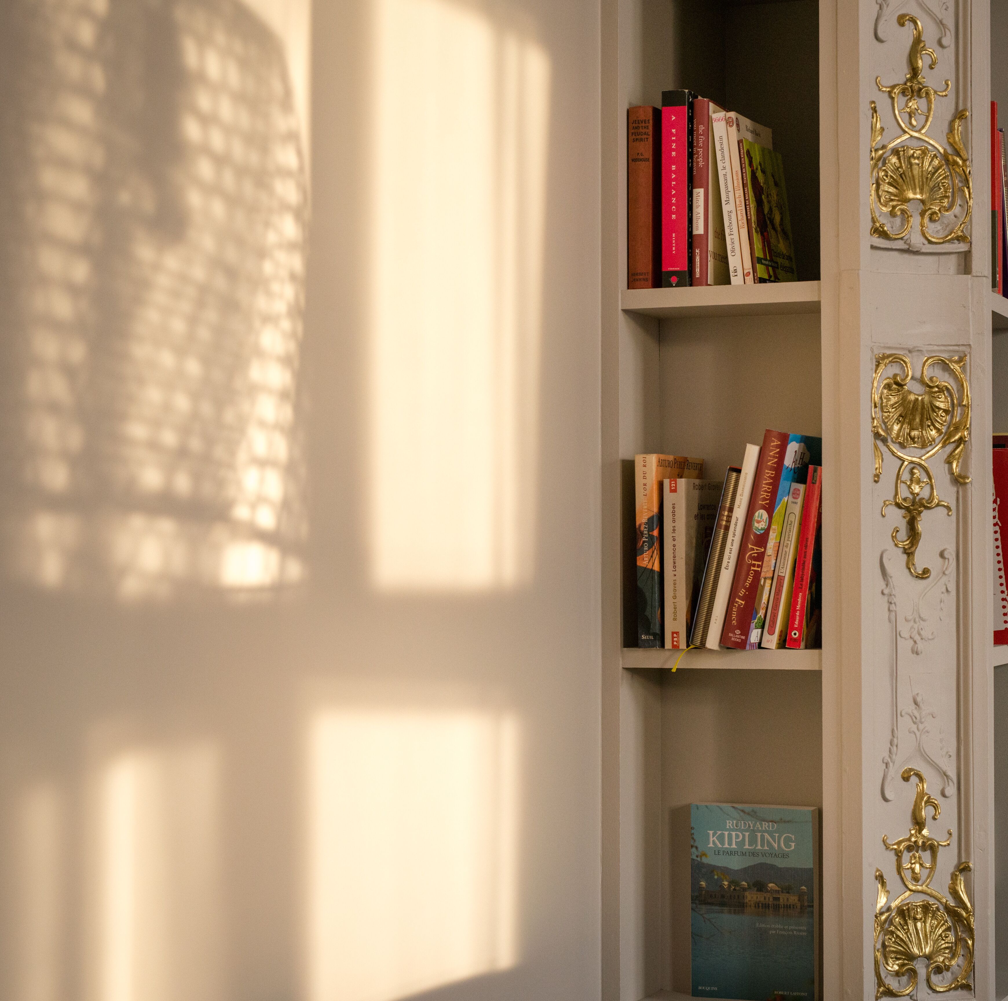 Une bibliothèque remplie de livres et un cadre de porte décoratif de couleur or.