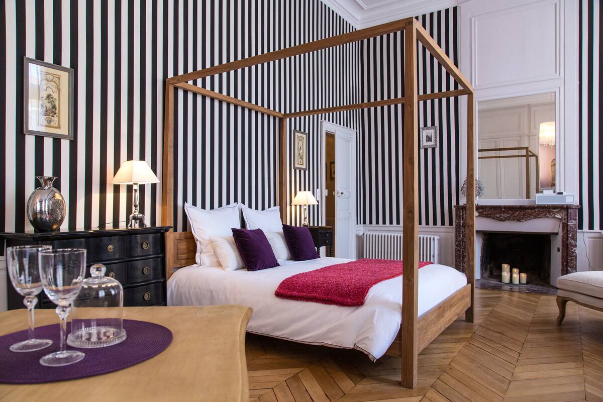 Una habitación con cama con dosel, chimenea y zona de comedor con mesa y sillas.