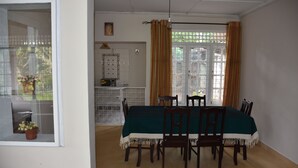 Comedor con una mesa dispuesta para cuatro personas, sillas alrededor, una ventana con cortinas y vistas al exterior.