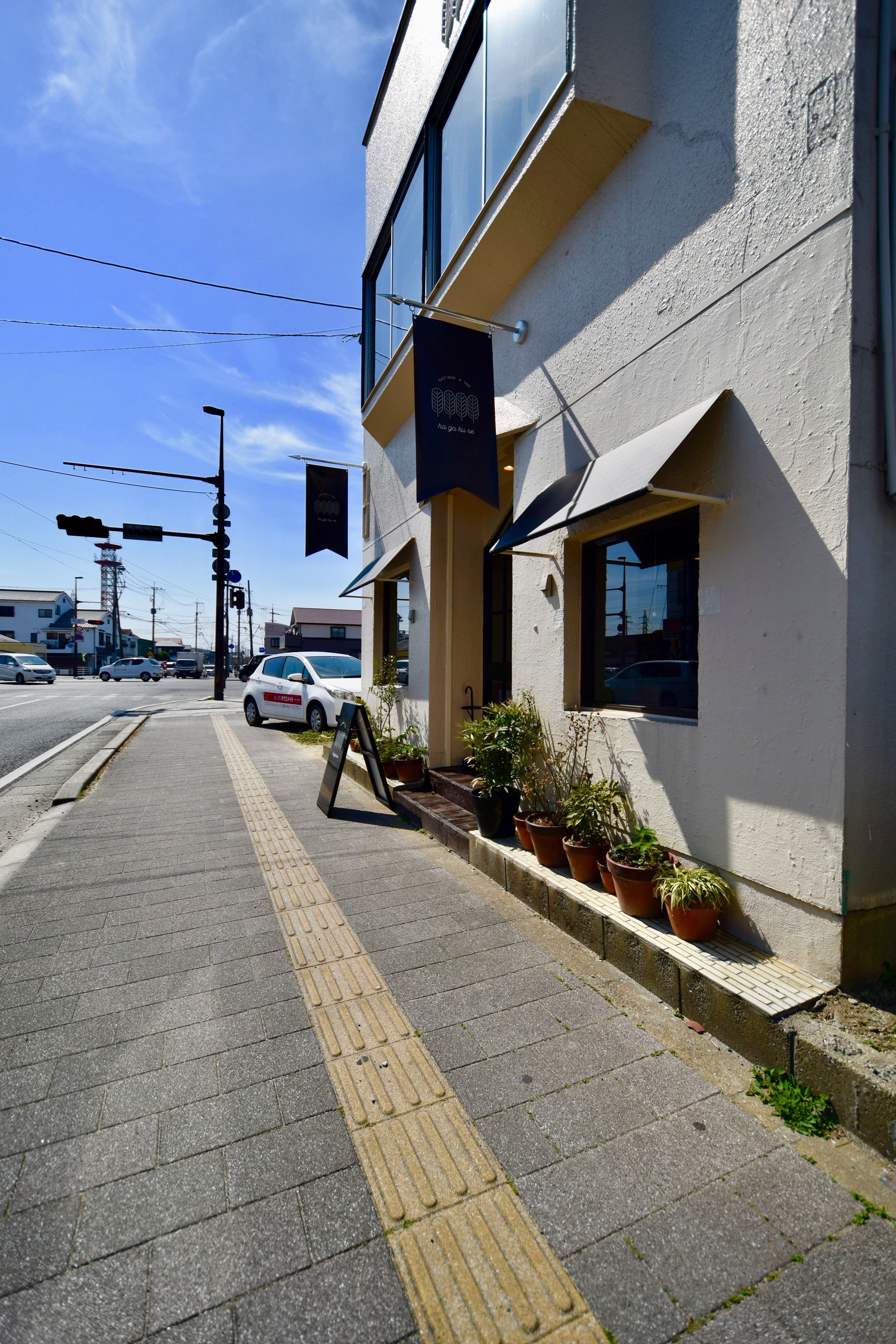 A building with a clear sidewalk, potted plants, and a signboard.