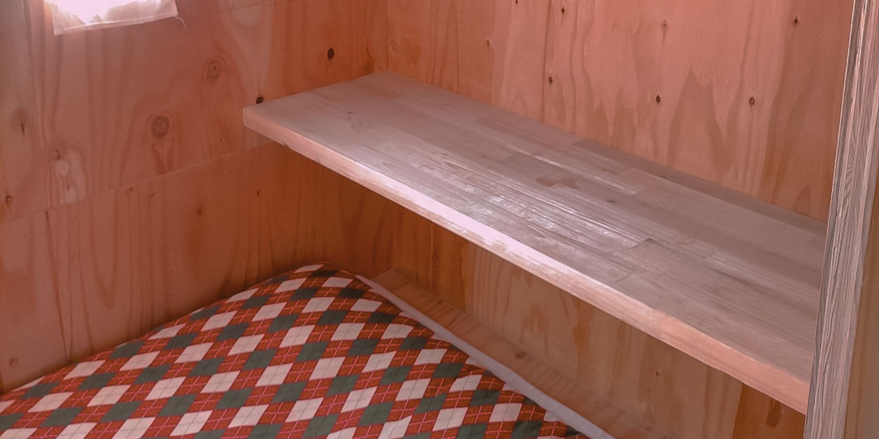 Una habitación de madera con un banco y una estantería de madera.