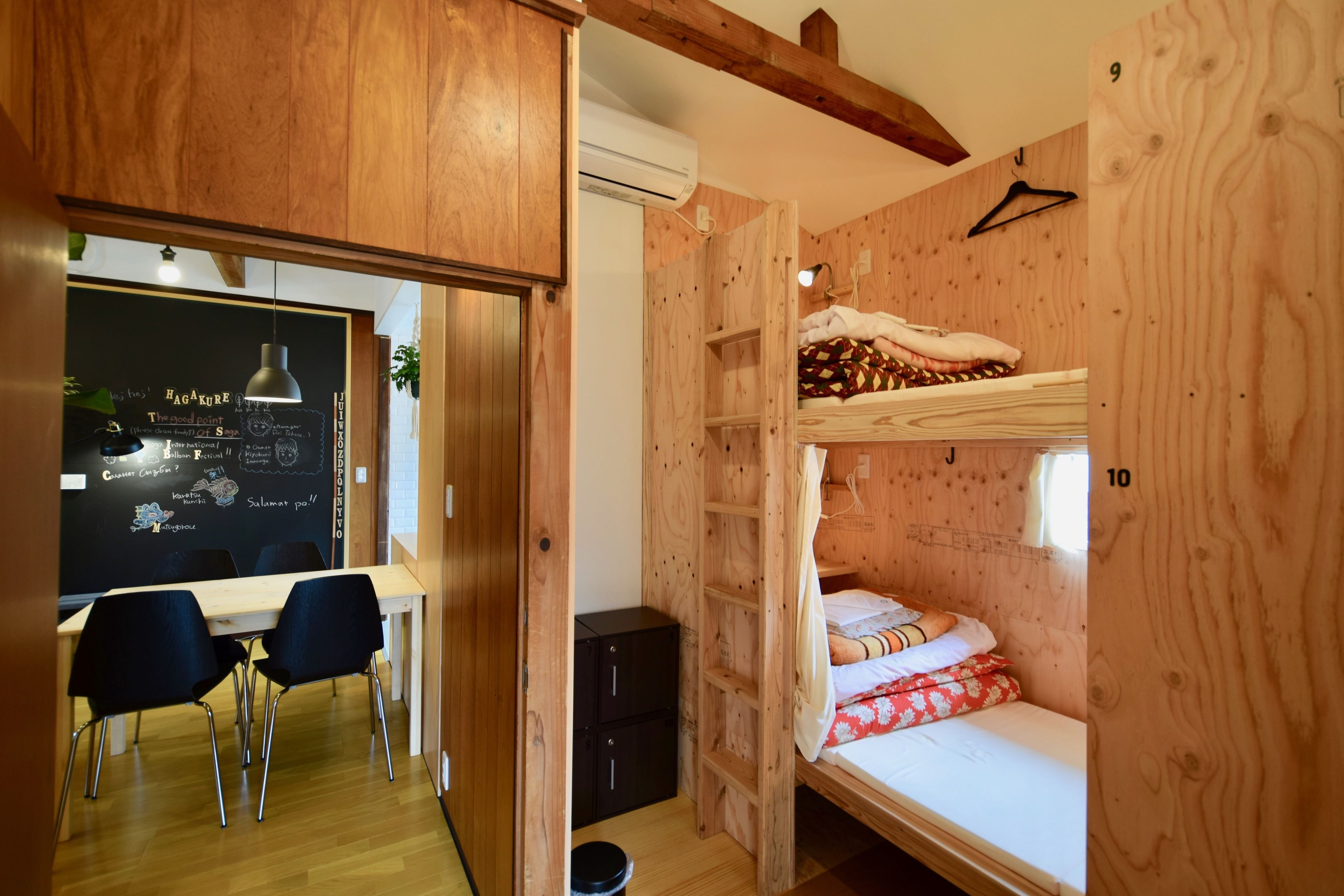 Une pièce en bois avec des lits superposés, un bureau avec des chaises et un tableau noir avec des inscriptions.