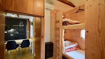 Une pièce en bois avec des lits superposés, un bureau avec des chaises et un tableau noir avec des inscriptions.