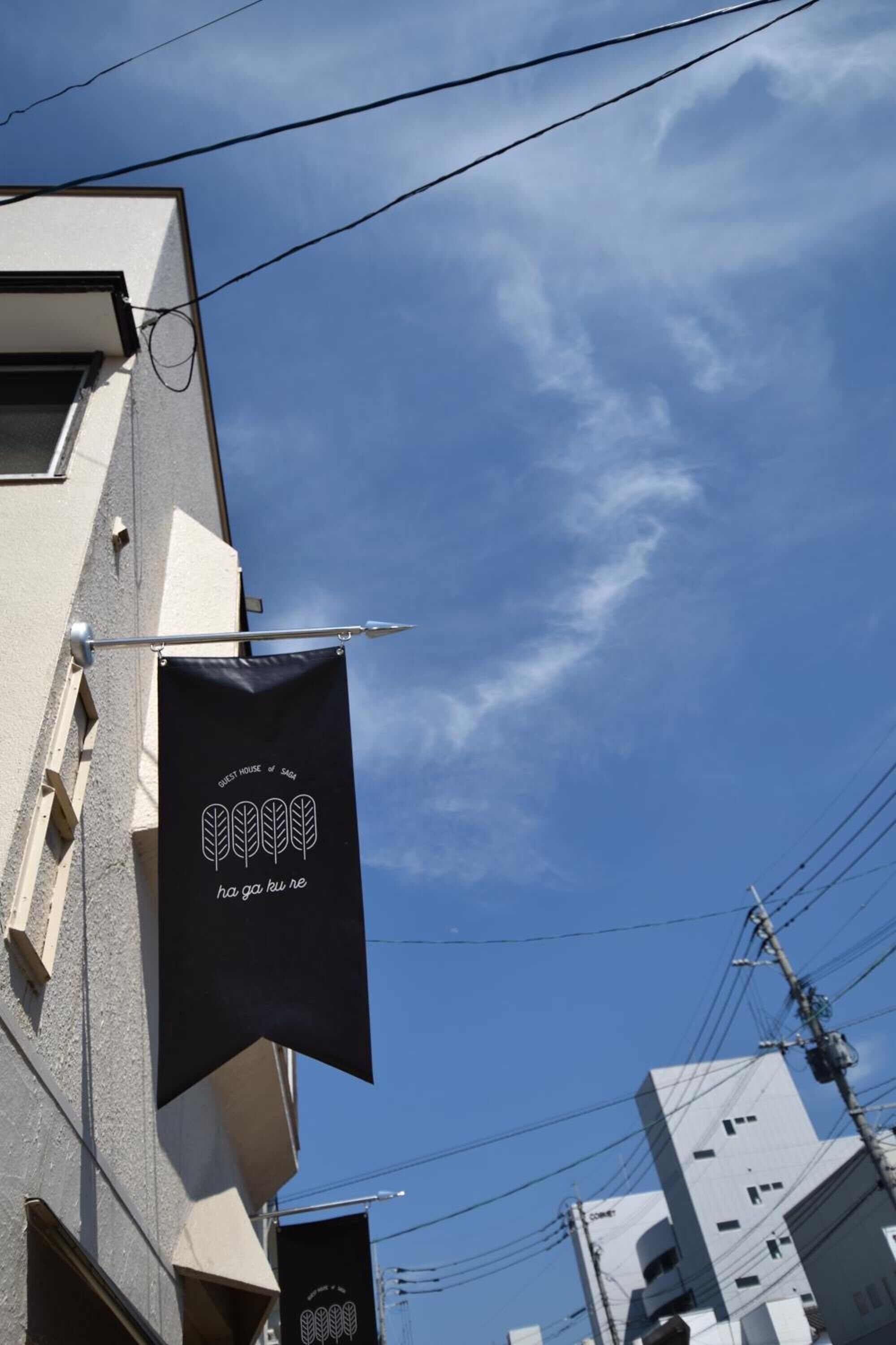 Ein Gebäude, an dem ein schwarzer Banner mit Schriftzug und Blattform hängt.