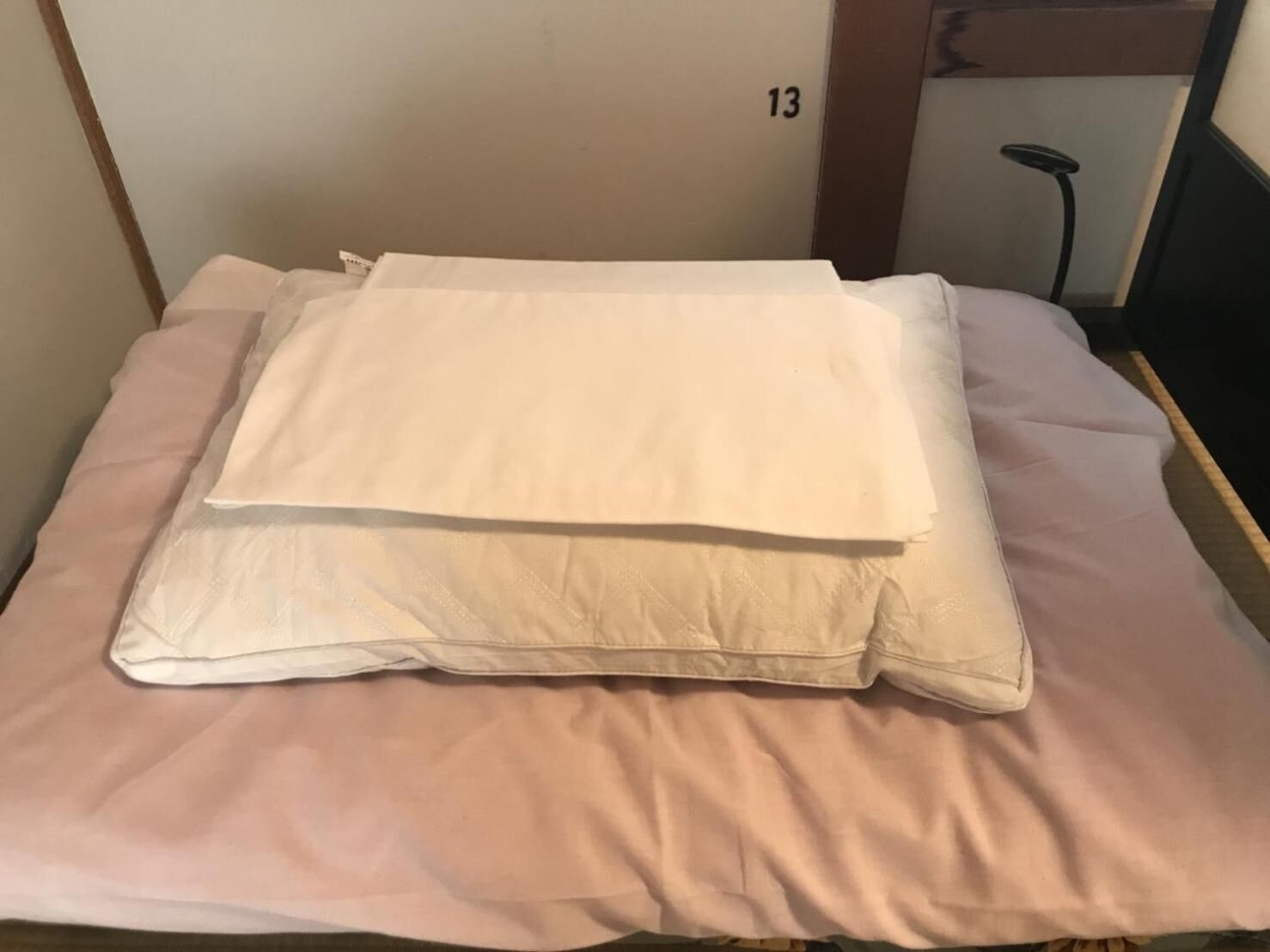 Un lit avec un matelas blanc et une couverture rose.