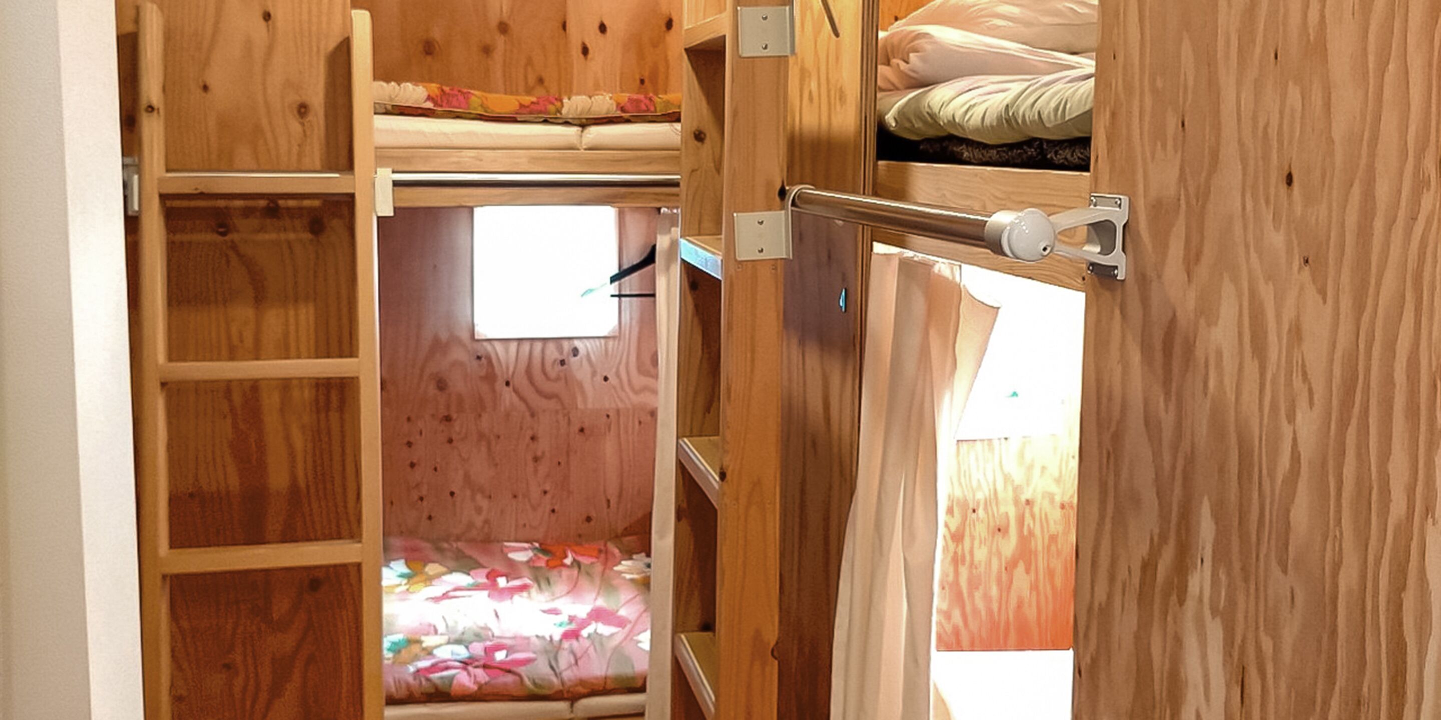 A compact, wooden interior with a bunk bed and a small window.