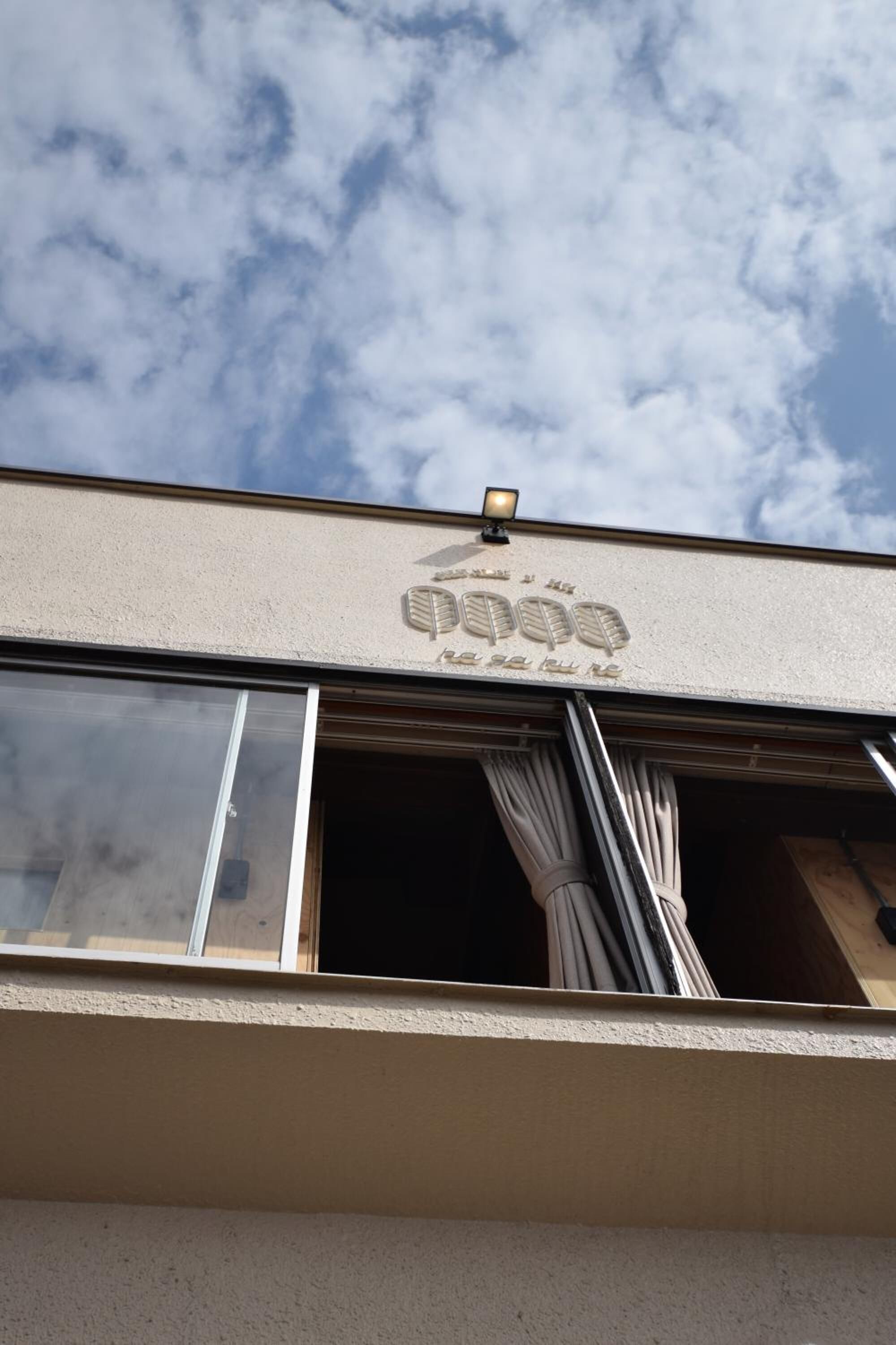 Ein Gebäude mit einer beigefarbenen Fassade, einem großen Fenster und einer halb geöffneten Tür.