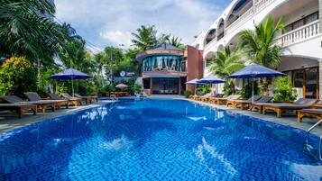 Een buitenzwembad, ligstoelen bij het zwembad