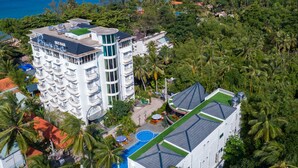 Un hotel de varios pisos con balcones, piscina y vista al océano.