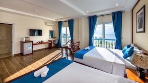 Habitación de hotel con dos camas, un escritorio, un televisor y un balcón con vistas.