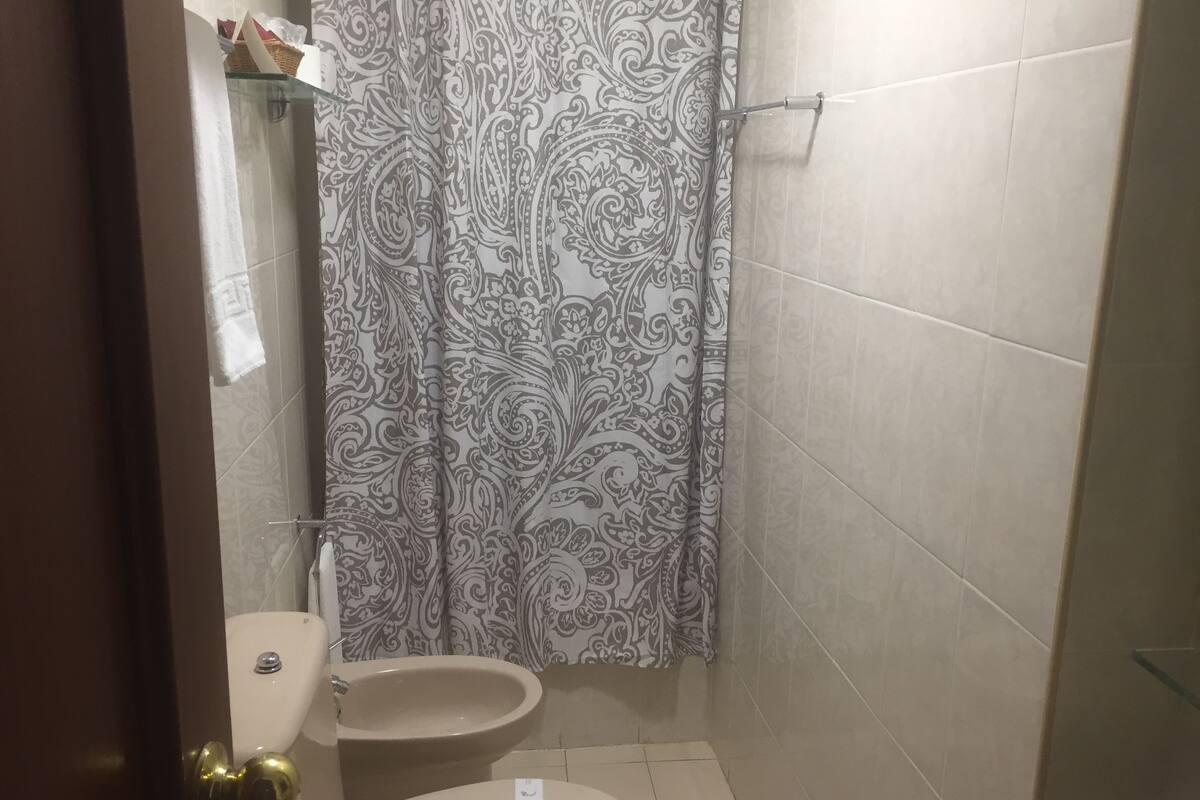 Un baño con inodoro, bidé y cortina de ducha estampada.