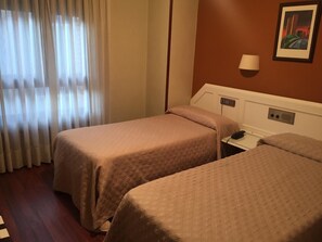 A hotel room with two beds, a bedside table, a lamp, and a painting on the wall. - Hotel Ovetense (Oviedo)