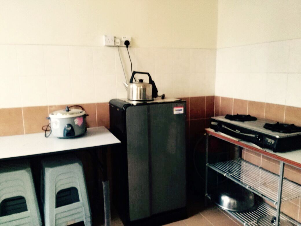 A compact kitchen with a refrigerator, a kettle, and a stove.